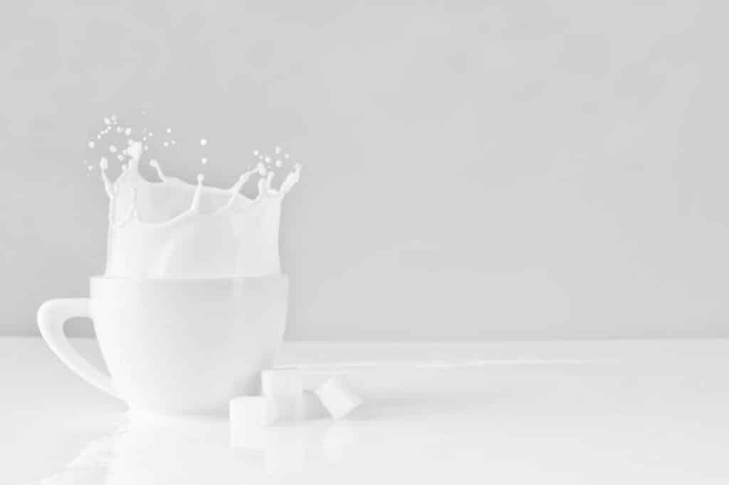 sugar block dropped on white cup with milk